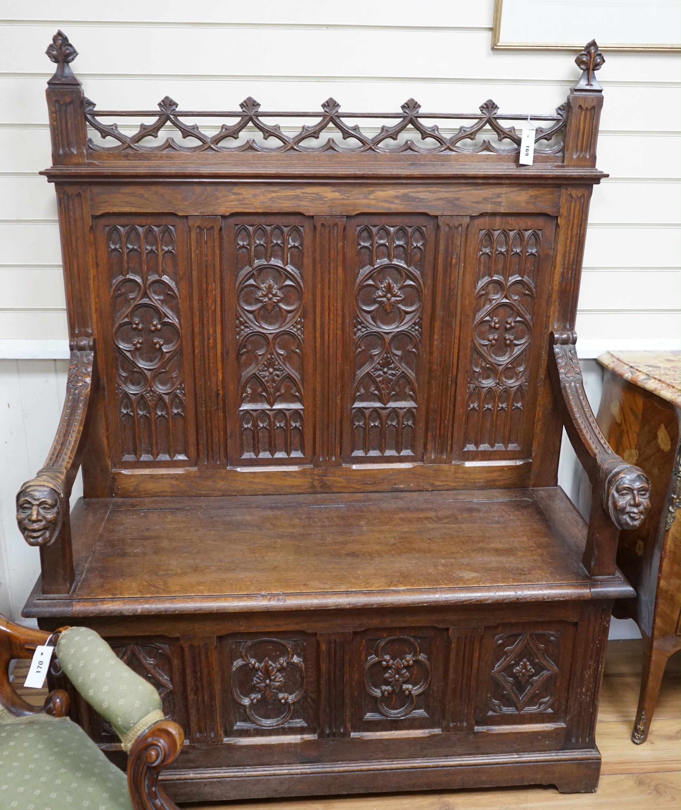 An early 20th century Gothic style carved oak box seat settle, length 116cm, depth 45cm, height 154cm